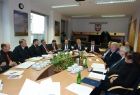 Grupa osób siedzących przy owalnym stole. W tle na ścianie godło Małopolski.