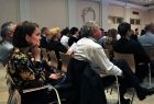 na zdjęciu widoczni są uczestnicy sympozjum siedzący na krzesłach