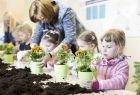 Na zdjęciu dzieci sadzące kwiatki w doniczkach