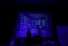 Zdjęcie przedstawia Małopolskie Spotkanie Teatrów Amatorskich pod nazwą POSIADY TEATRALNE na Orawie. Na zdjęciu są 3 osoby, słabo widoczne, zdjęcie jest prześwietlone kolorem niebieskim.