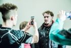 Zdjęcie przedstawia mężczyznę, któremu dwie inne osoby robią zdjęcie telefonami komórkowymi. Zdjęcie zrobiono podczas spektaklu pt.:Vernon Subutex w Teatrze im. J. Słowackiego w Krakowie.