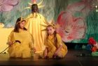 Zdjęcie przedstawia zespół teatralny Stonoga; dwie dziewczynki w żółtych strojach siedzą na podłodze, trzecia stoi odwrócona tyłem. 