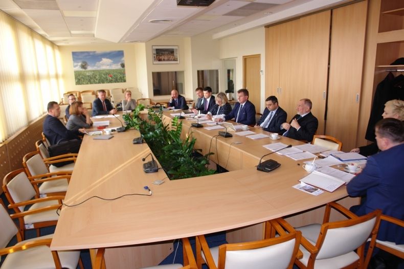 Grupa osób siedzących przy prostokątnym stole.