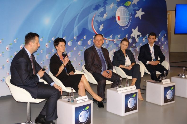 Grupa ludzi siedzących przy stolikach z logiem EKS.