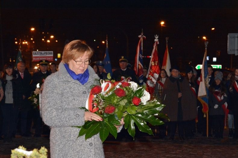 Radna M. Mordarska trzymająca biało-czerwony bukiet. W tle poczty sztandarowe.