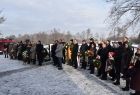 Grupa osób stojących w rzędzie z wiązankami kwiatów.