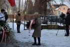 Iwona Gibas składa biało-czerwoną wiązankę pod tablicą pamiątkową.