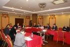 Grupa osób siedzących przy stołach ułożonych w literę u.