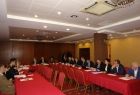 Grupa osób siedzących przy stołach ułożonych w literę u.
