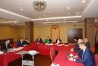 Grupa osób siedzących przy stołach ułożonych w literę u.