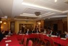 Grupa osób siedzących przy stołach ułożonych w literę u.