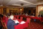 Grupa osób siedzących przy stołach ułożonych w literę u.
