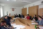 Grupa osób siedzących przy owalnym stole. W tel na ścianie godła Małopolski i Polski.