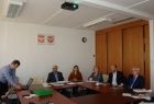 Grupa osób siedzących przy trzech stołach ułozonych w literę c. Na ścianie za środkowym stołem godła Małopolski i Polski.