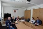 Grupa osób siedzących przy owalnym stole. W tle na ścianie godło małopolski i napis-województwo małopolskie.