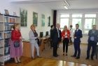 Grupa osób stojących na tle regału z książkami.
