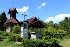 Zdjęcie przedstawia budynek - kaplicę otoczoną zielonymi krzewami
