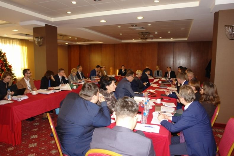 Grupa osób siedzących przy stołach ułożonych w literę u.