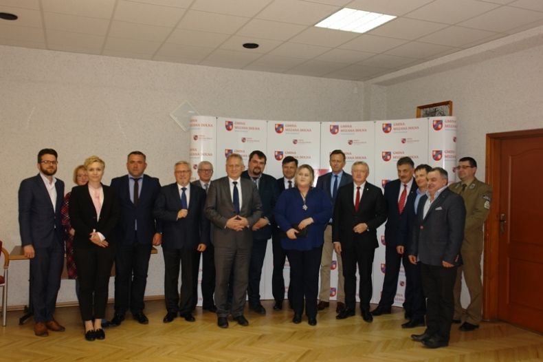 Grupa osób pozujących do zdjęcia na tle ścianki z herbem i napisem gmina Mszana Dolna.