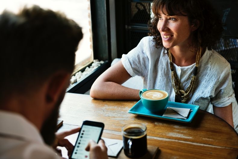 Zdjęcie przedstawia dwie osoby rozmaiwające przy kawie