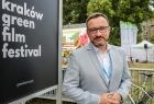 mężczyzna w garniturze stoi obok tablicy z napisem: Kraków green film festiwal