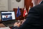 Łukasz Smółka siedzi przodem do kompuetra, ale na zdjęciu widać tylko mężczyznę od tyłu, za to w całości widać ekran komputera, widok od tyłu