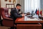 mężczyzna w garniturze siedzi przy drewnianym biurku, widok z profilu