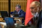 Sesja Sejmiku Województwa Małopolskiego. Na pierwszym planie przewodniczący Jan Tadeusz Duda w trakcie lektury, spoglądający w monitor. W tle flaga narodowa. Nieco dalej marszałek Witold Kozłowski sporządzający notatki.