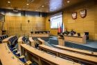 Widok na salę obrad Sejmiku Województwa Małopolskiego. Półkoliste rzędy foteli stoją puste. Sesja sejmiku, z powodu pandemii, miała charakter zdalny.
