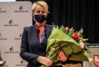 Iwona Gibas z zarządu województwa z kwiatami na tle ścianki Małopolski