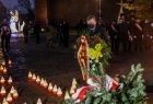 Mężczyzna składa kwiaty przed Krzyżem Katyńskim, zbliżenie
