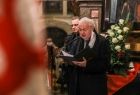 Mężczyzna przemawiający podczas mszy, na pierwszym planie fragment flagi