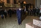 Mężczyzna stojący przed pomnikiem, z pochyloną głową