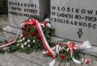 Zbliżenie na kwiaty przed pomnikiem Bogdana Włosika