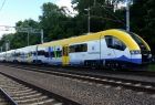 pociąg jadący po torach pomalowany na żółto, biało i niebiesko