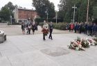 Delegacja dwóch mężczyzn z wieńcem na placu przed pomnikiem