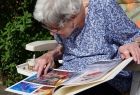 starsza kobieta czyta gazetę, siedząc na krześle