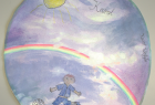 Pierwsza nagroda. Autor: Aurelia Ciszek. Obrazek w kształcie koła. Karol Wojtyła jako chłopiec grający w piłkę na tle błękitnego nieba, słońca i tęczy