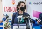 Marta Malec-Lech z zarządu województwa stoi i mówi do mikrofonów. W tle widoczny napis Tarnów i Małopolska.