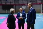 Przedstawiciele Stowarzyszenia Europejskich Komitetów Olimpijskich złożyli wizytę w Tauron Arenie Kraków, wizytowali także Centrum Kongresowe ICE Kraków. Trzech mężczyzn rozmawia stojąc na boisku w hali sportowej