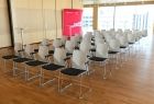 Jasne, przestronne pomieszczenie w centrum konferencyjnym. Zbliżenie na kilka rzędów równo ustawionych foteli