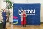 kobieta i mężczyzna na tle granatowej ścianki konferencyjnej z napisem MCDN