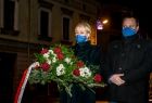 Mężczyzna i kobieta składający kwiaty przed tablicą pamiątkową