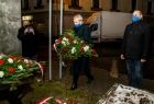 Kobieta kładzie wieniec przed tablicą pamiątkową