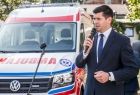 Uroczyste przekazanie karetek. Plac przed Krakowskim Pogotowiem Ratunkowym. Przemawia wicemarszałek Łukasz Smółka. W tle nowy ambulans