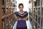 kobieta z książką między regałami w bibliotece