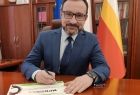 Wicemarszałek Tomasz Urynowicz podpisuje certyfikat dla Miejsca Przyjaznego Rowerzystom, w tle wnętrze gabinetu