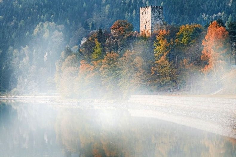 Widok na taflę jeziora i zamek spowite mgłą