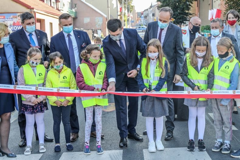 mężczyzna z dziećmi przecina wstęgę na drodze