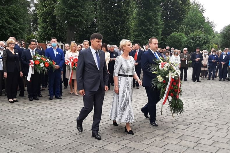 Zdjęcie kobiety i dwóch mężczyzn składających kwiaty podczas uroczystości